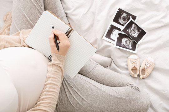 Pregnant woman writing to-do-list, top view, free space