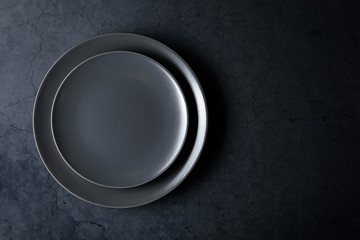 Empty black plate on a old stone cracked table. Top view.