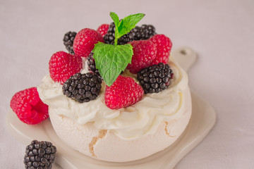 Delicious Pavlova meringue cake decorated with whipped cream, fresh   blackberries, raspberries and mint.
