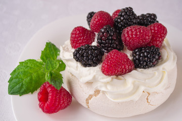 Homemade meringue cake Pavlova with whipped cream, fresh blackberries and raspberries on the top. Delicious dessert.
