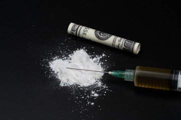 Cocaine or other illegal drugs, white powder, syringe, isolated on black glossy background