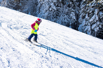 Fototapeta na wymiar Young skier skiing in mountain ski resort during winter vacation