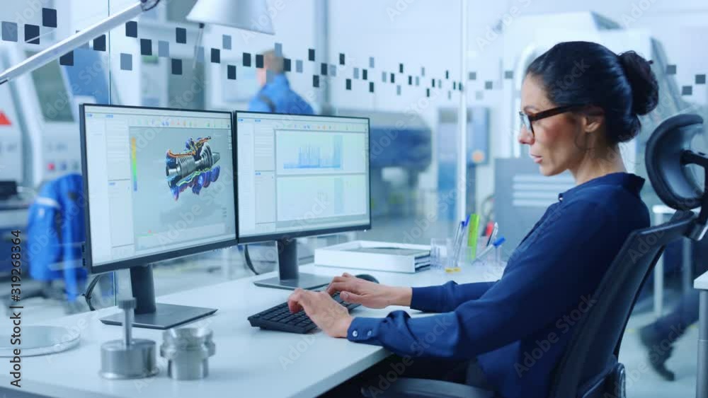 Poster Female Industrial Engineer Solving Problems, Working on a Personal Computer, Two Monitor Screens Show CAD Software with 3D Prototype of Zero-Emissions Engine Being Tested. Working Modern Factory