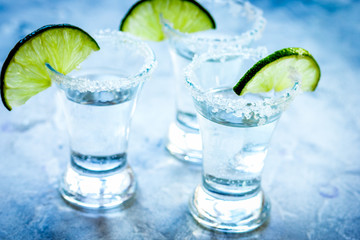 Silver tequila shots with lime and salt on gray stone background