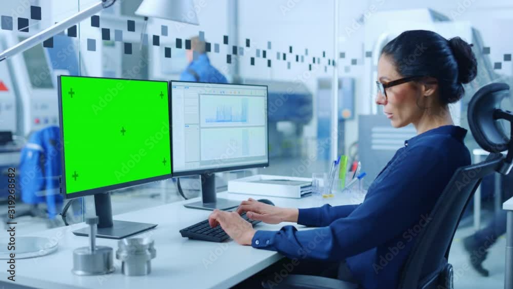 Poster Female Engineer Working on a Personal Computer, Two Monitor Screens Show Chroma Key / Green Screen Display and CAD Software with 3D Model of Industrial Machinery Mechanism. Working Modern Factory