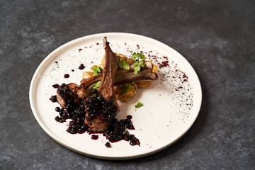 Lamb ribs with baked potatoes on a white plate, close-up.