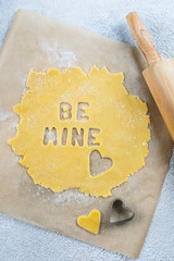 Bakery Valentine's Day Concept. Be mine text. Making homemade heart shaped cookies from shortbread raw dough. Top view