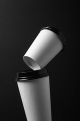 tower of different size white paper coffee cups with black lid on black background