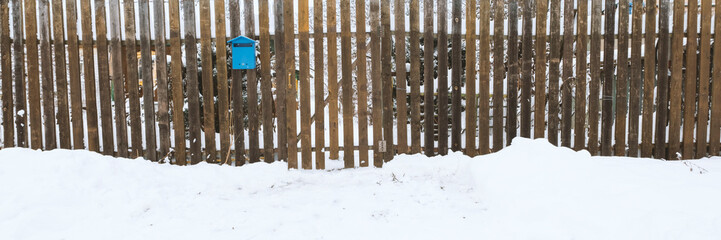 Snow field or street and old fence with blue postbox . Great background with copyspace. Winter and snow landscape. Stock photo.