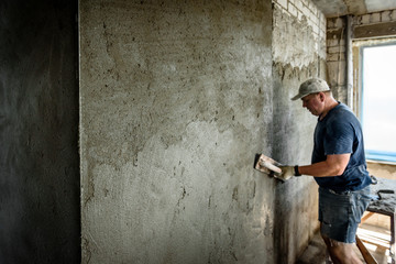 Worker applying plaster on the wall using a trowel.