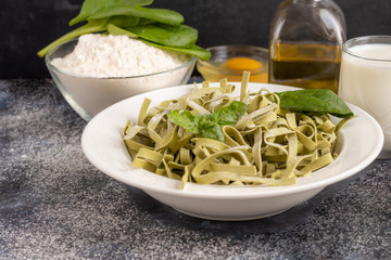 Pasta, vegetables, herbs and spices, olive oil, ingredients for Italian cuisine on a dark background.