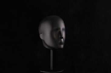 black mannequin head isolated on black background