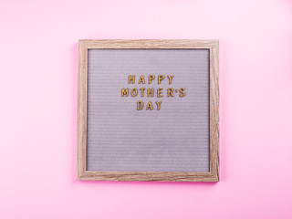 Mother's day greetings on wooden letter board on pink trendy monochrome backdrop. Copy space flat lay