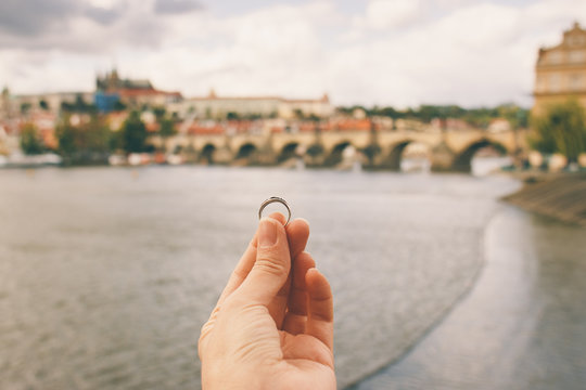 Woman holding an engagement ring front The Charles Bridge. An offer of marriage in Prague, Czech Republic. Film effect, author processing of photo