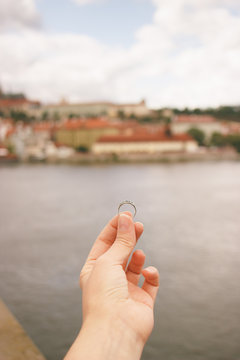 Woman holding an engagement ring front The Charles Bridge. An offer of marriage in Prague, Czech Republic. Film effect, author processing of photo