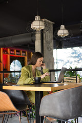 Obraz na płótnie Canvas Beautiful stylish businesswoman freelancer sitting at cafe and working on her laptop.
