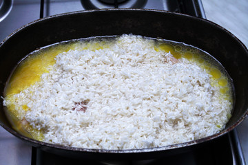 cooking pilaf in stages on a gas stove in a cauldron
