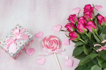 pink satin hearts, candy, a bouquet of pink roses, a gift in a box