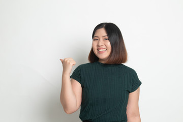 Young Asian woman smile and point to copy space with her thumb