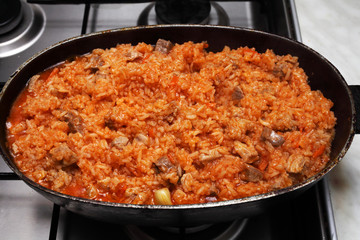 cooking pilaf in stages on a gas stove in a cauldron