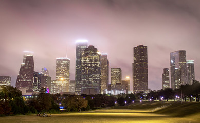 Houston Texas city skyline and green field park on a cloudy foggy evening	