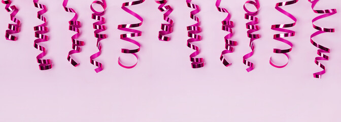 Purple curly ribbons on pastel pink background.