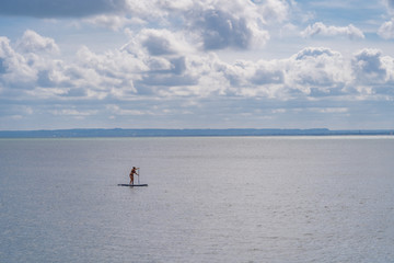 Luc-Sur-Mer, France - 08 16 2019:  View of the sea from the beach with a paddling woman