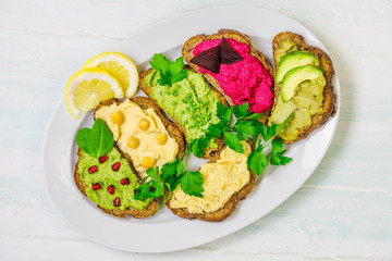 Different kinds of dips bread with humus. Traditional with chickpeas and sesame seeds , herbs with spinach leaves, avocado and beetroot hummus, 
