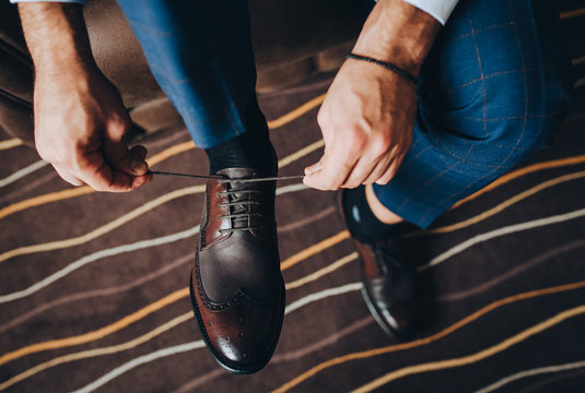 Close-up of a man, groom, businessman tying shoelaces on brown expensive shoes. Morning businessman preparing for work. Photography, concept.