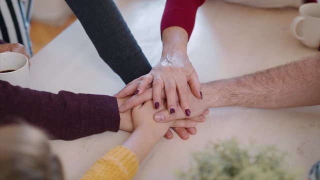 A group of people at community centre, stacking hands together.
