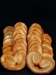 Sweet palmier biscuits over back background.