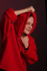 Studio portrait of a dark-haired boy, on a maroon background, in a red hoodie jacket