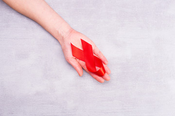 Aids red ribbon on woman's hand support for World aids day and national HIV AIDS and aging awareness month concept