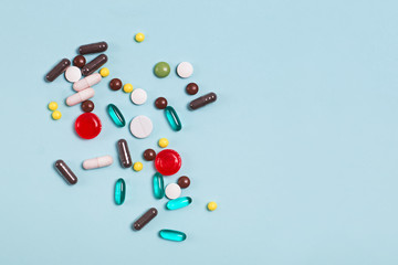 Different multi colored pills and tablets on blue background.