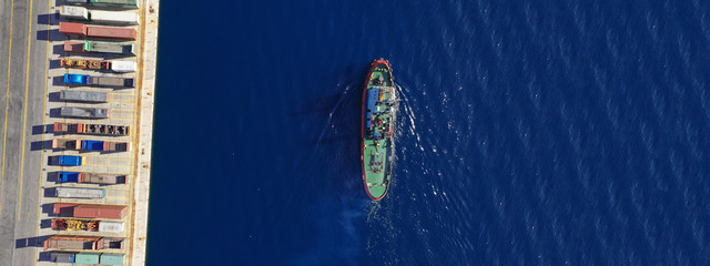 Aerial drone ultra wide photo of assisting tug boat cruising in Mediterranean logistics port with...