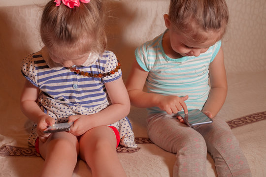 two small girls playing by phone at home