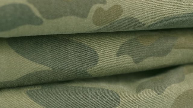 Rotate pan shot of green camouflage fabric. Closeup dolly macro shot of a military camo cloths. Cloths. Shot in 6k.