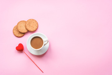 A cup of coffee, cookies and  red toy heart on pink background. Love concept, Valentines day. Top view, flat lay, copy space.