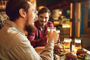 A group of friends is sitting in a bar with glasses of beer.