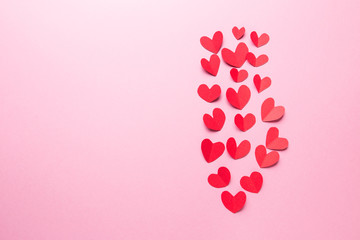A lot of small hearts of red color against on a pink background. Happy Valentine's Day.