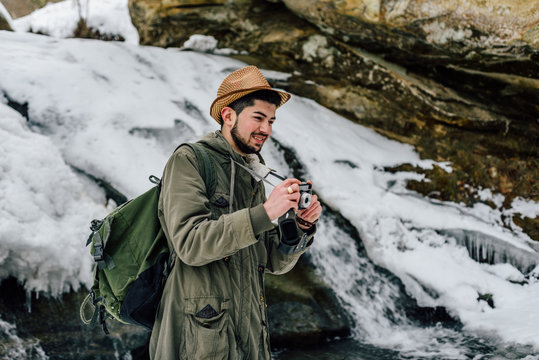 Professional photographer posing near a frozen waterfall on mountains
