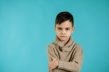 offended sad little child boy on blue background. Human emotions and facial expression