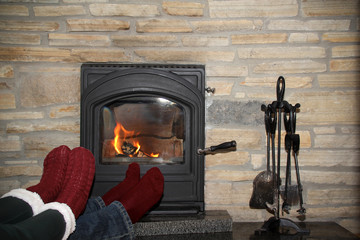 male and female legs in burgundy socks near the hot fire of a burning fireplace, Christmas concept