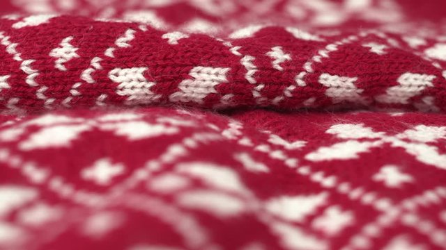 Dolly shot pan shot of soft warm knitted red and white Christmas woolen fabric. Rotated macro shot of fluffy winter design wool textile, cloth, blanket. Knitwear. Shot in 6k.