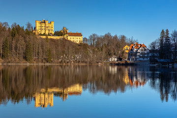 Fototapeta na wymiar Stunning view of the Alpsee lake in winter on a sunny day with the Hohenschwangau Castle and Bavaria Alps in background, with beautiful reflections in water, Schwangau, Bavaria, Germany