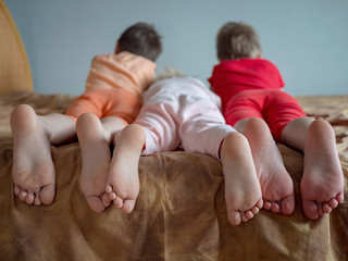 Three brother boys were lying on couch and were busy with phone and tablet. boys are wearing...
