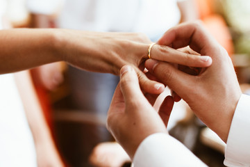 Obraz na płótnie Canvas Man putting wedding ring on woman finger. Exchange Wedding rings. happy groom and bride. Wedding day concept.