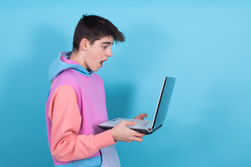 young teenage man or student with laptop isolated on background with surprise or success expression