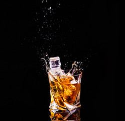 Whiskey with splash on black background, brandy in a glass