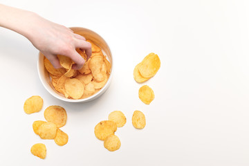 Hand graps potato chips from bowl on white background